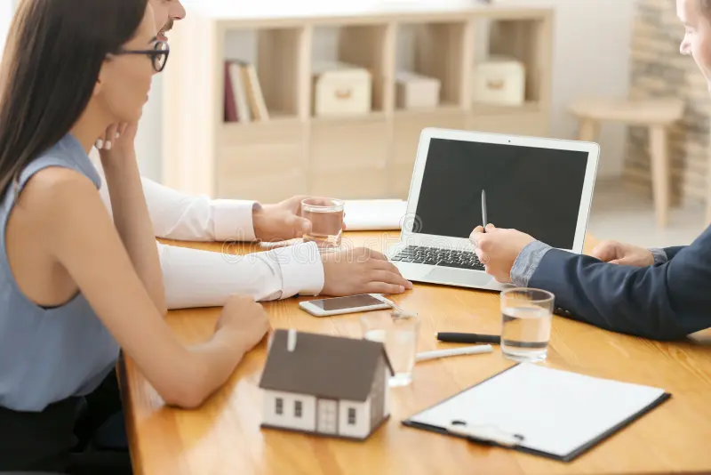 Real estate consultation with model house and laptop